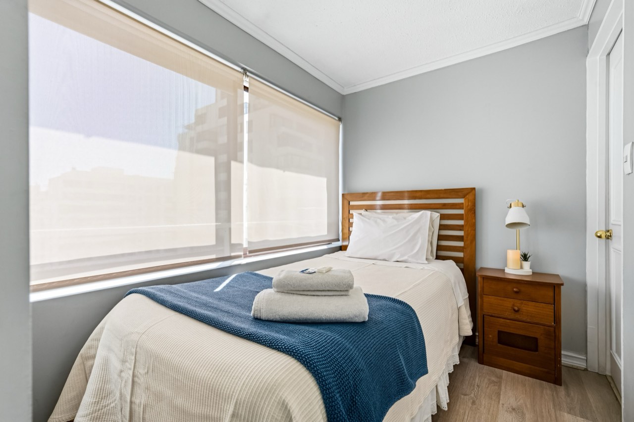 Dormitorio individual con cabecera de madera - Suite 1001 Suites Vitacura