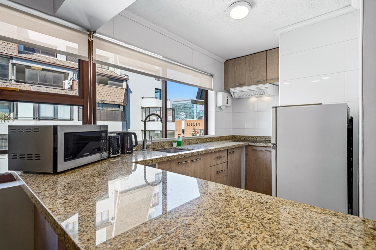 Cocina con mesón de granito y microondas - Suite 1001 Suites Vitacura