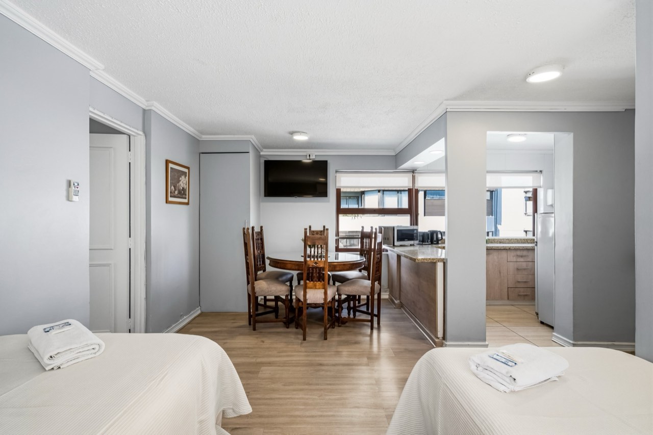 Vista amplia con camas, comedor y cocina - Suite 1001 Suites Vitacura