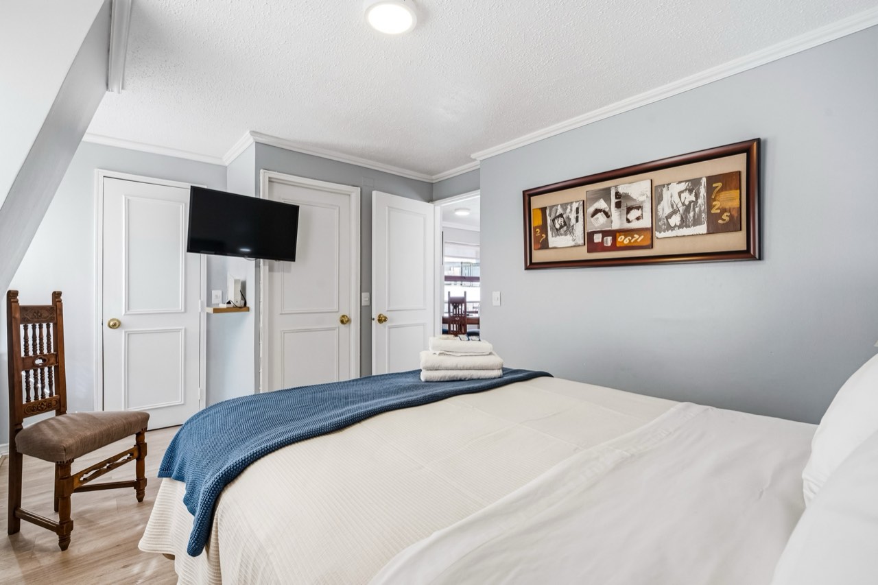 Dormitorio principal con TV y closet - Suite 1001 Suites Vitacura