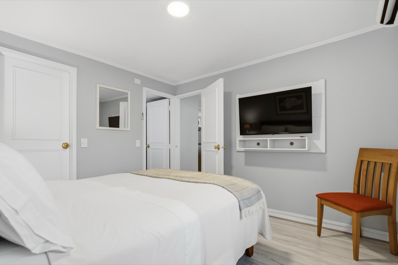 Dormitorio con cama matrimonial y TV - Suite 106 Suites Vitacura