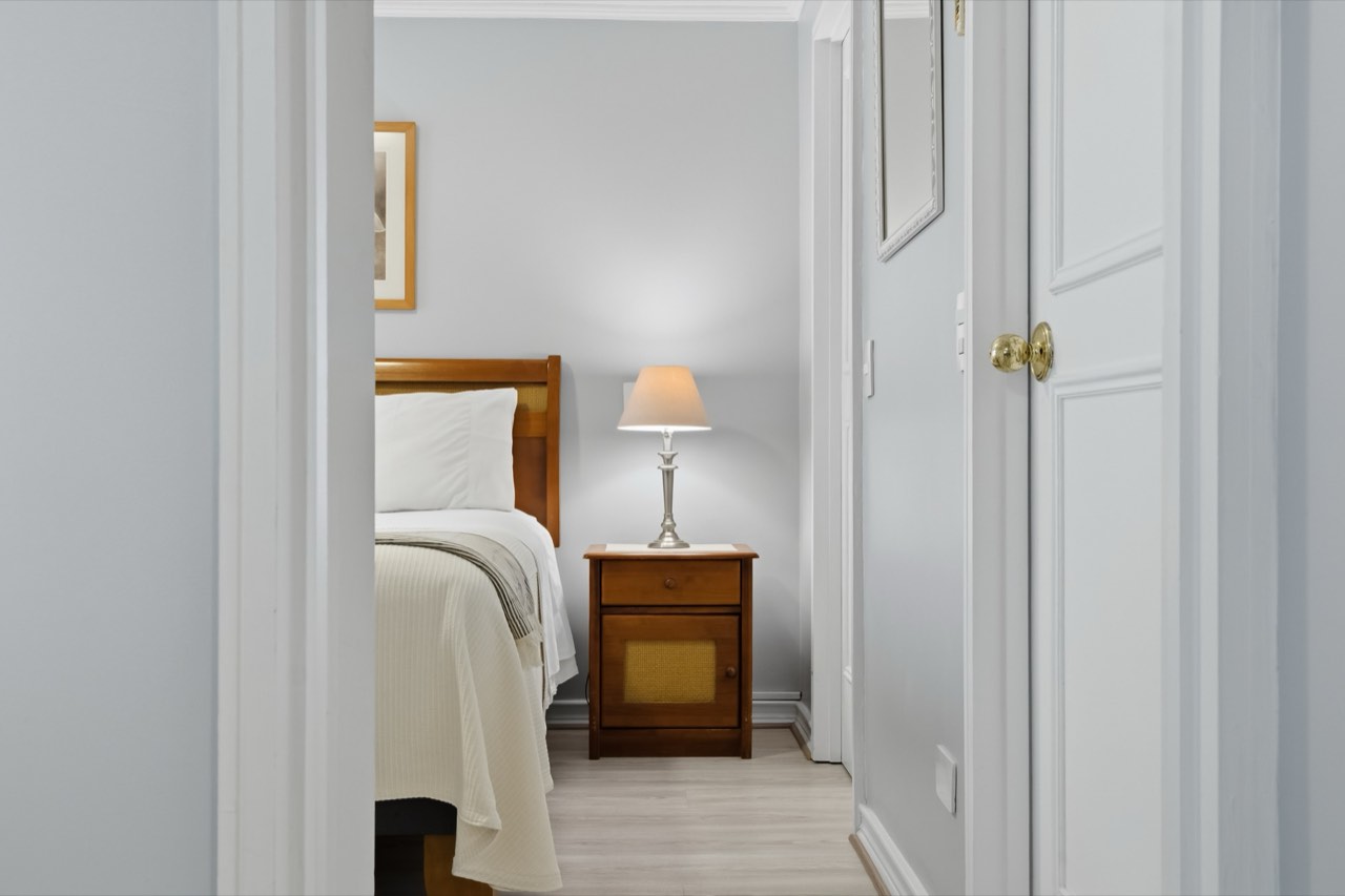 Dormitorio con velador y lámpara decorativa - Suite 106 Suites Vitacura