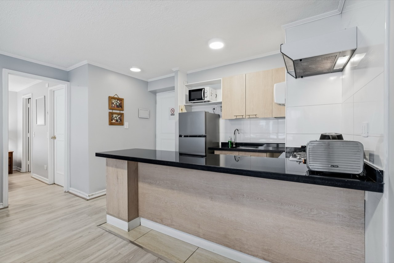 Cocina con mesón amplio y vista al comedor - Suite 106 Suites Vitacura