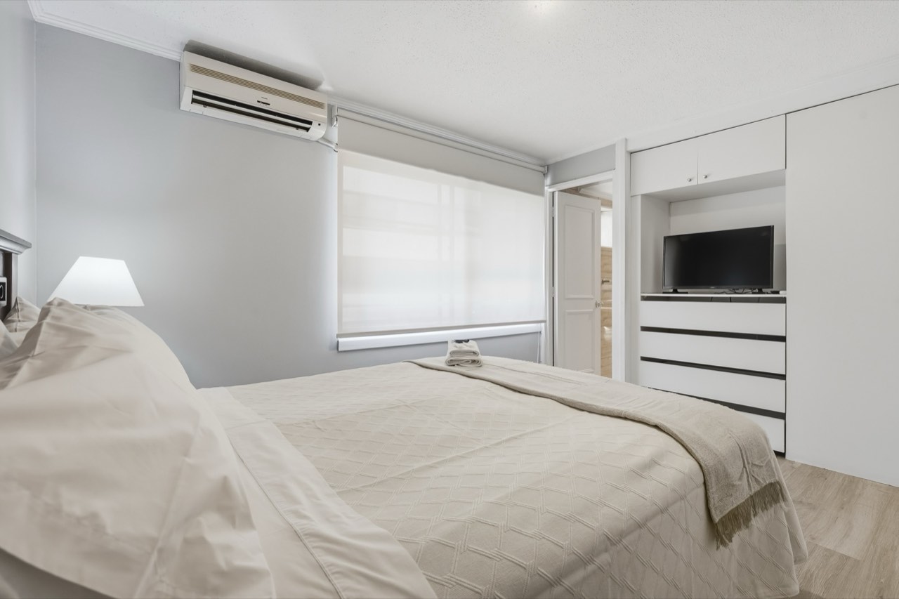 Dormitorio con aire acondicionado y ventana - Suite 405 Suites Vitacura