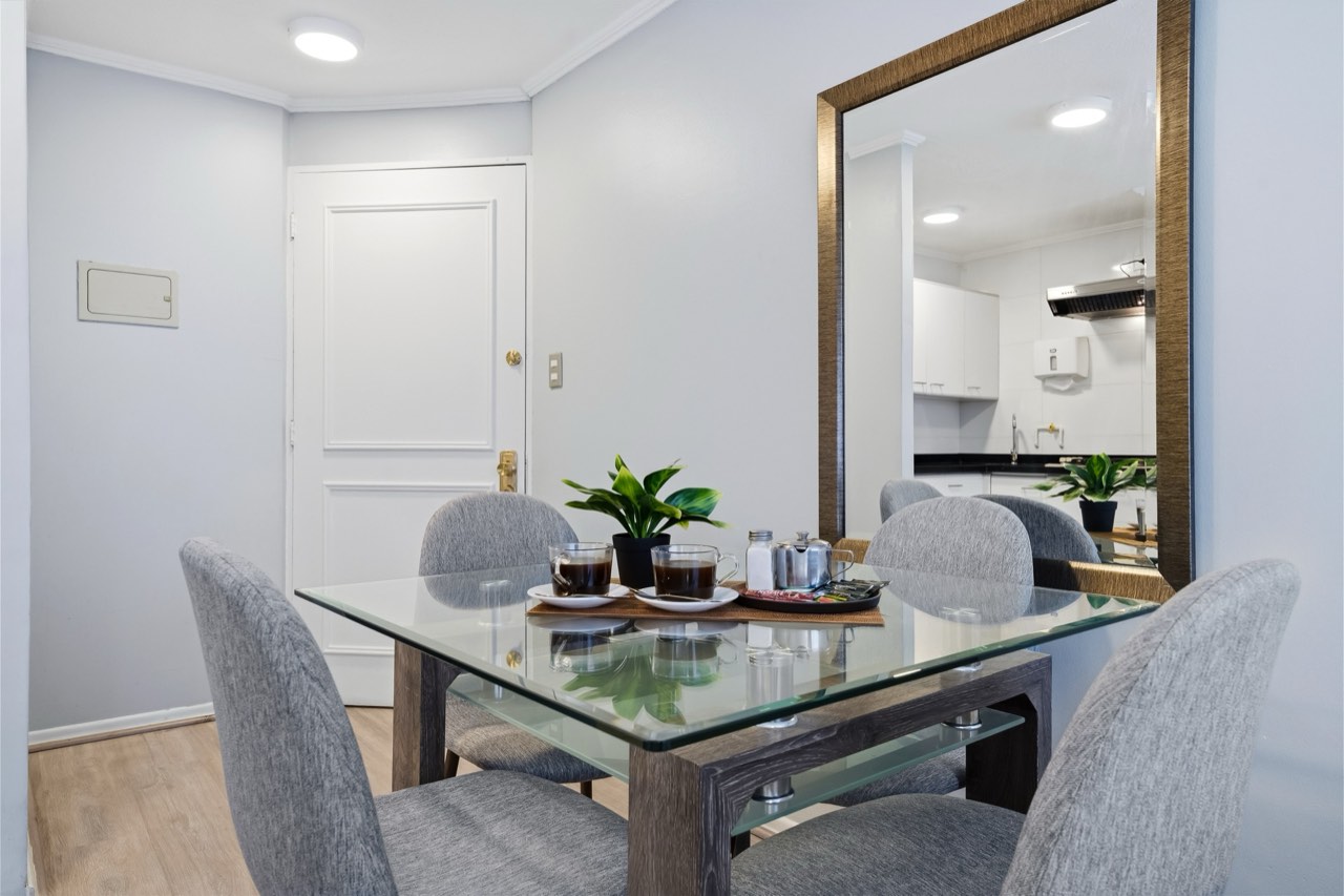 Comedor con mesa de vidrio y sillas - Suite 405 Suites Vitacura