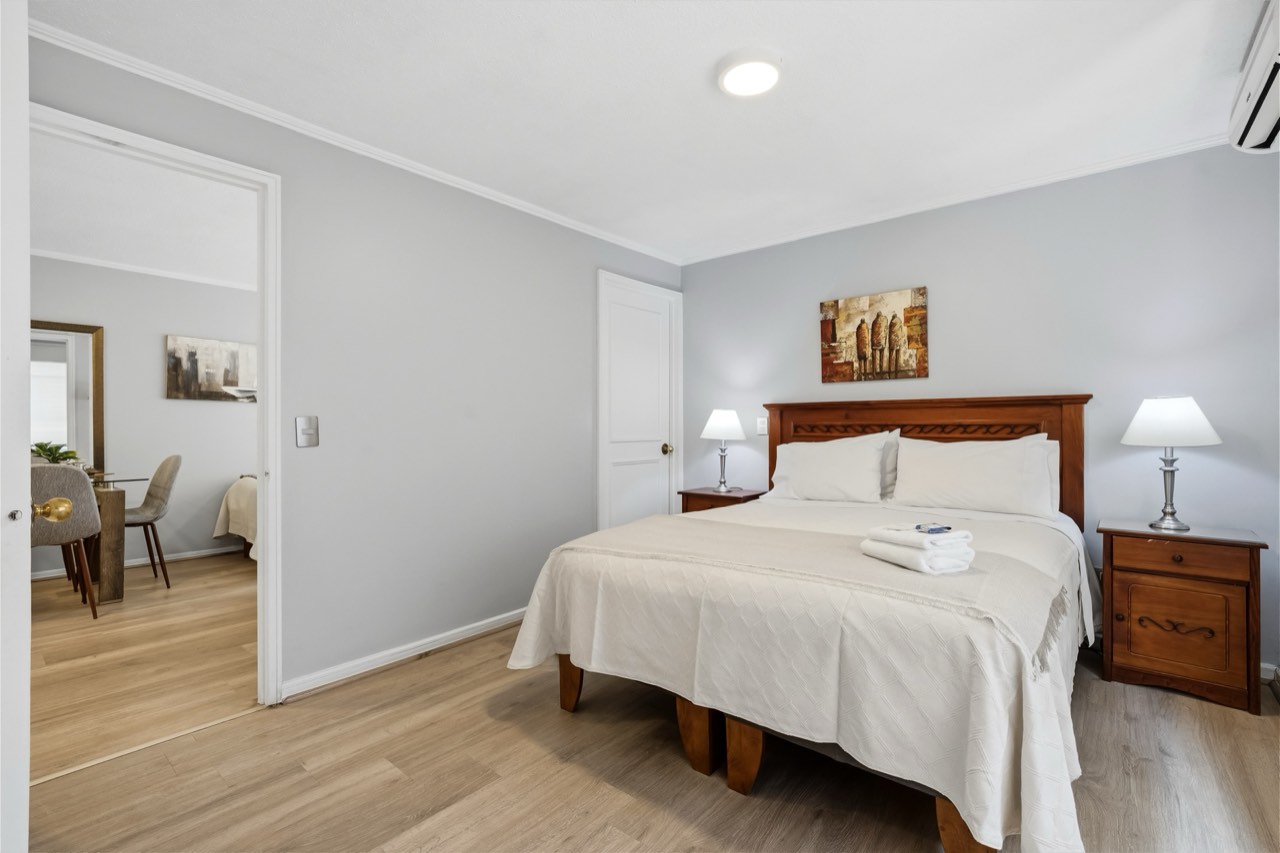 Dormitorio con cama y cabecera de madera tallada - Suite 405 Suites Vitacura