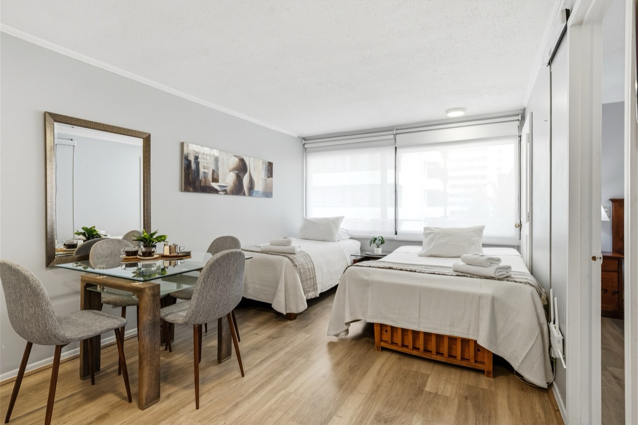 Living comedor con dos camas y mesa de vidrio - Suite 405 Suites Vitacura