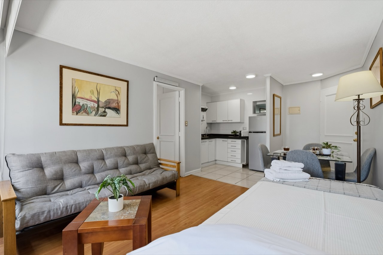 Sofá y cama con vista a kitchenette - Suite 605 Suites Vitacura