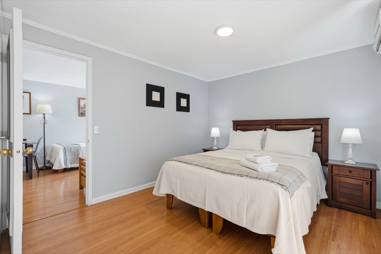 Dormitorio con cama matrimonial y vista al living - Suite 605 Suites Vitacura