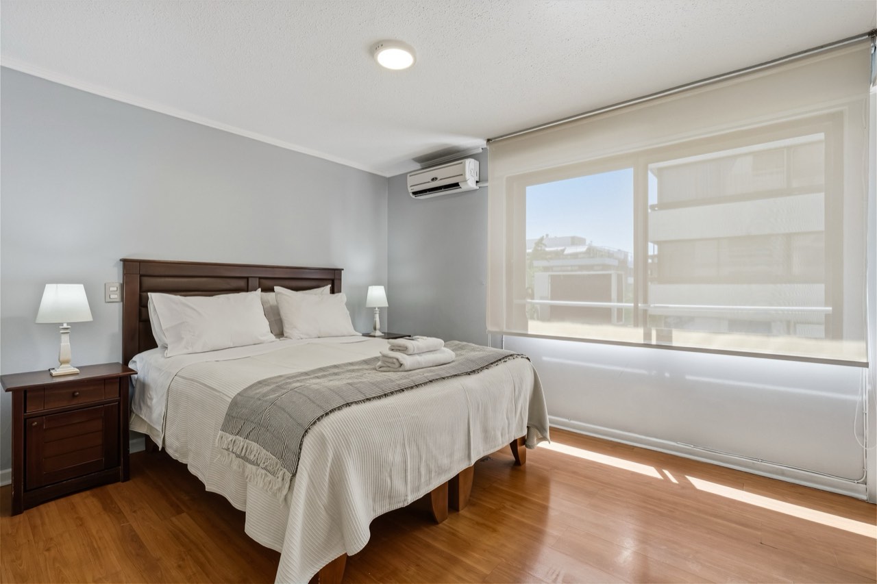Dormitorio con ventana y aire acondicionado - Suite 605 Suites Vitacura