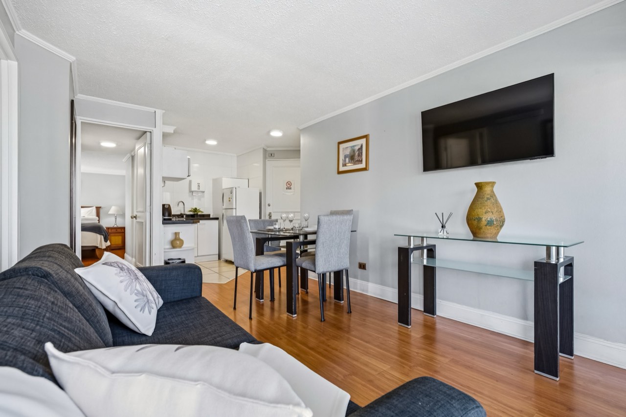 Living con sofá y televisor - Suite 701 Suites Vitacura