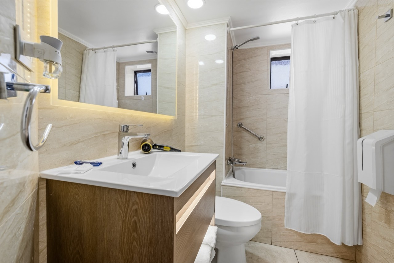 Baño con tina y cortina decorativa - Suite 801 Suites Vitacura