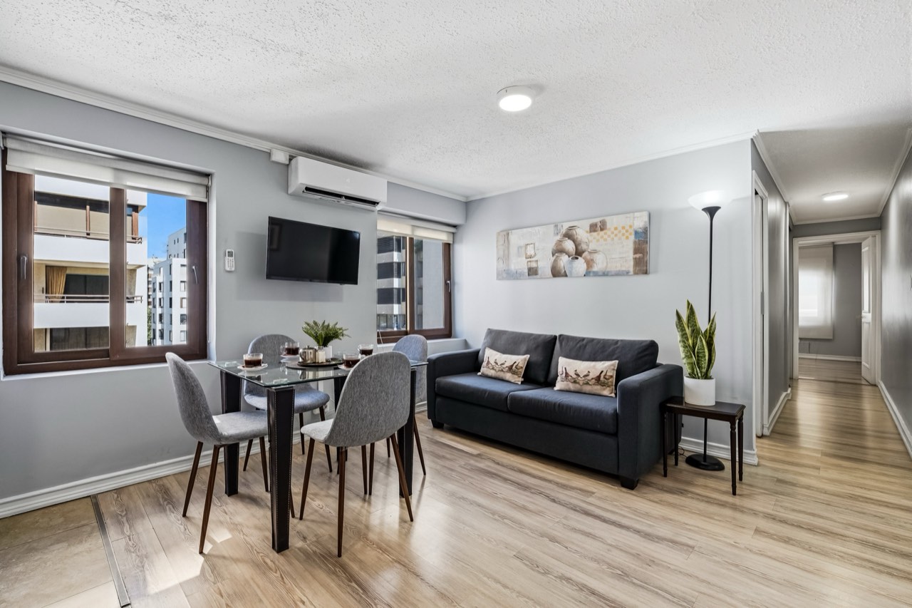 Living comedor con sofá y mesa de vidrio - Suite 803 Suites Vitacura