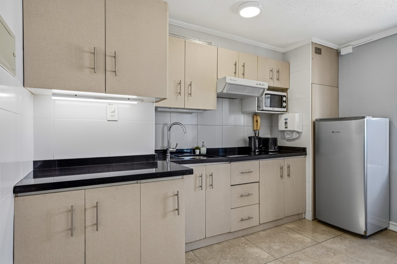 Cocina con mesón y refrigerador - Suite 803 Suites Vitacura