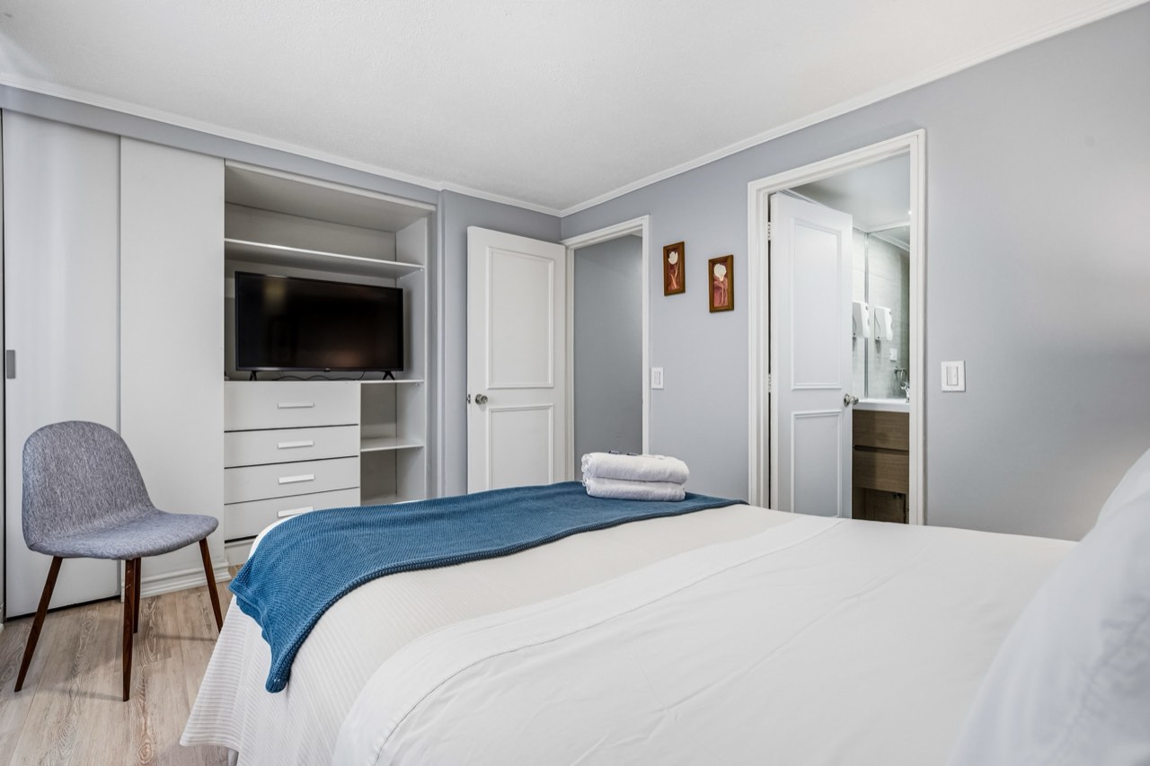 Dormitorio con closet y TV - Suite 803 Suites Vitacura